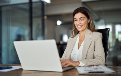 Woman happily typing on laptop for data analytics and Power BI - Allston Yale